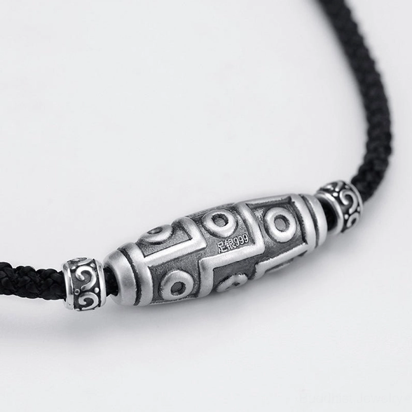 Front close-up of 999 sterling silver dzi bead showing clear hallmark stamp and intricate nine-eye carving detail