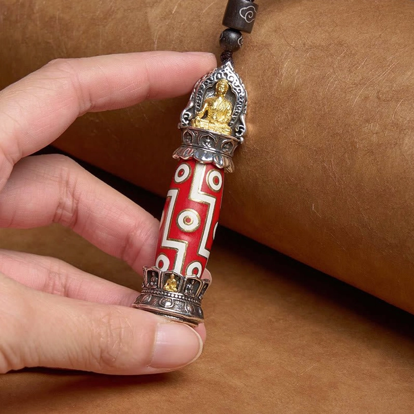 Buddhist Medicine Buddha Nine-Eye Dzi necklace held in hand showing red-white patterns and silver-gilt Buddha ornament