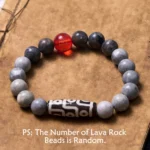 Nine-eye dzi bead picasso jasper bracelet flat lay with matte gray stone beads and red accent bead on vintage brown notebook background
