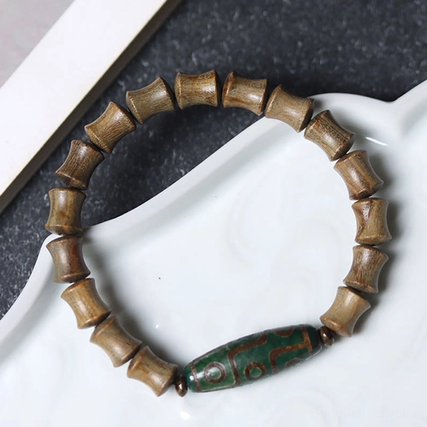 Green sandalwood Buddhist bracelet with nine-eye dzi bead close-up angled view