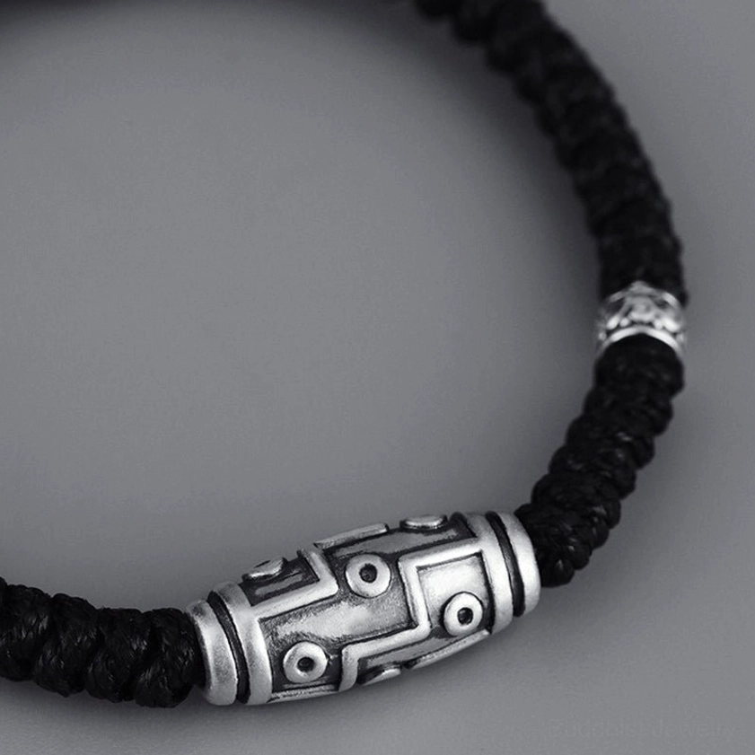 Close-up side profile of 999 sterling silver nine-eye dzi bead bracelet with antique finish and intricate dzi bead pattern