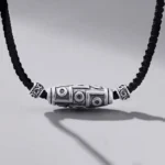 999 sterling silver nine-eye dzi bead necklace with black braided cord, front oblique view showing intricate carved dzi patterns