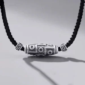 999 sterling silver nine-eye dzi bead necklace with black braided cord, front oblique view showing intricate carved dzi patterns