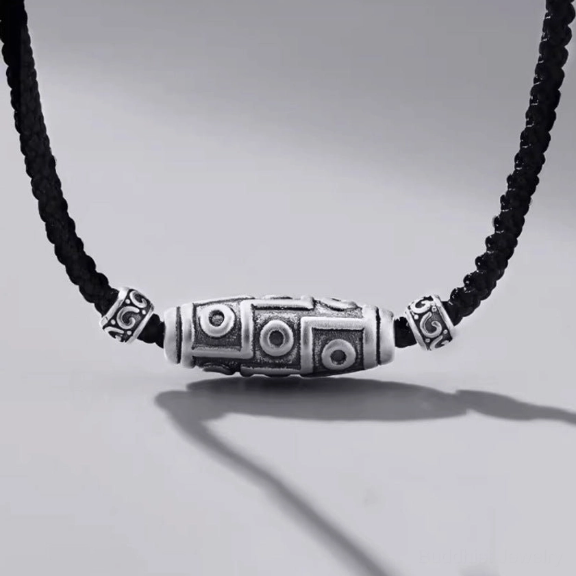 999 sterling silver nine-eye dzi bead necklace with black braided cord, front oblique view showing intricate carved dzi patterns