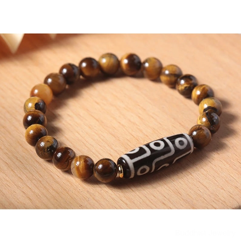 Nine-eye dzi protection bracelet featuring tiger eye stone beads and sacred dzi bead on desktop tray