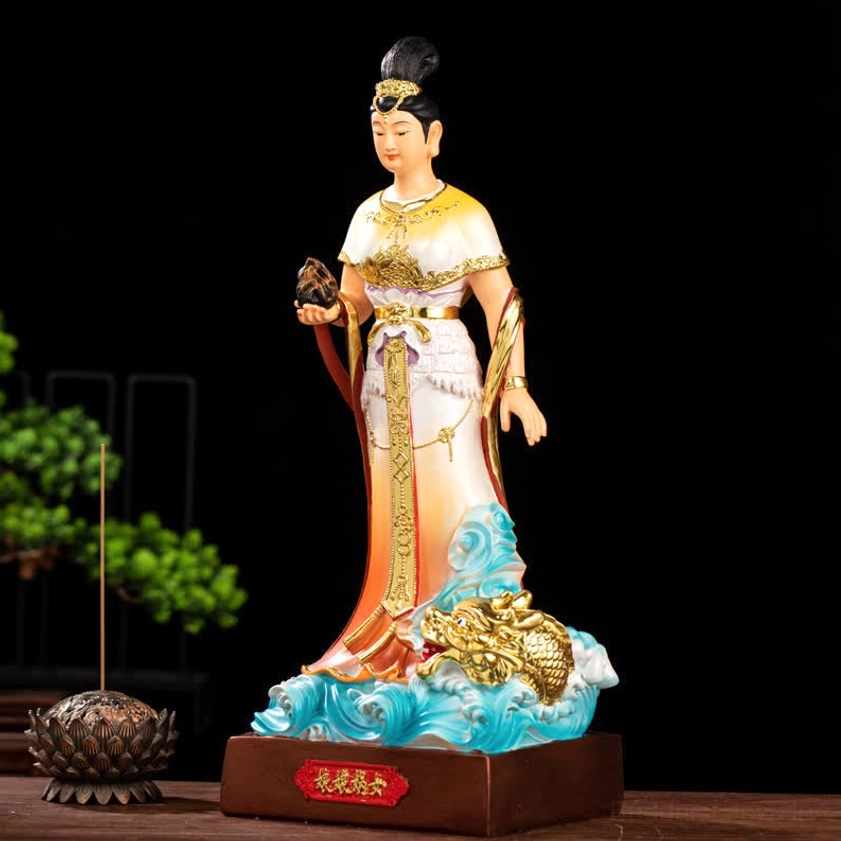 Nuwa Bodhisattva statue three-quarter angle showing detailed golden embroidery and sacred stone prop