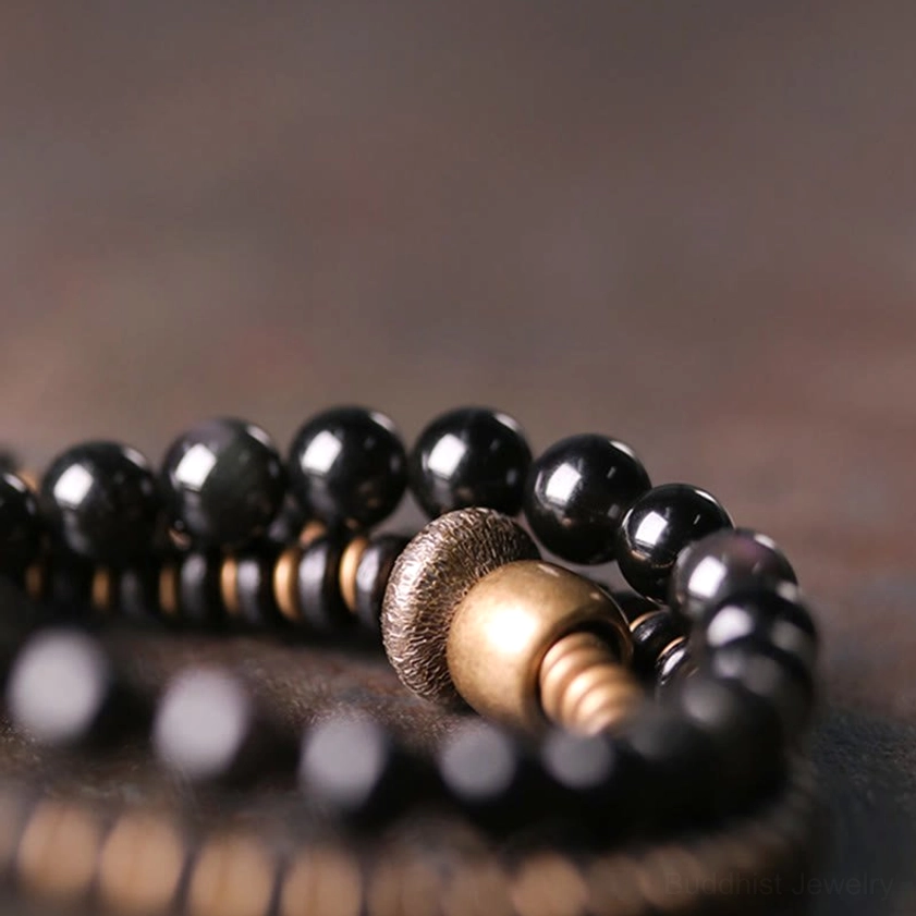 Smooth glossy black obsidian round beads with bronze-toned metal spacer components in triple wrap design