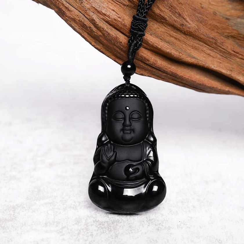 Obsidian Buddha pendant necklace with woven cord on wooden background - side view