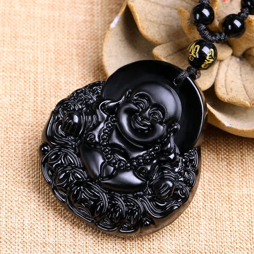 Black obsidian laughing Buddha pendant necklace with intricate carved details and beaded necklace - overhead view