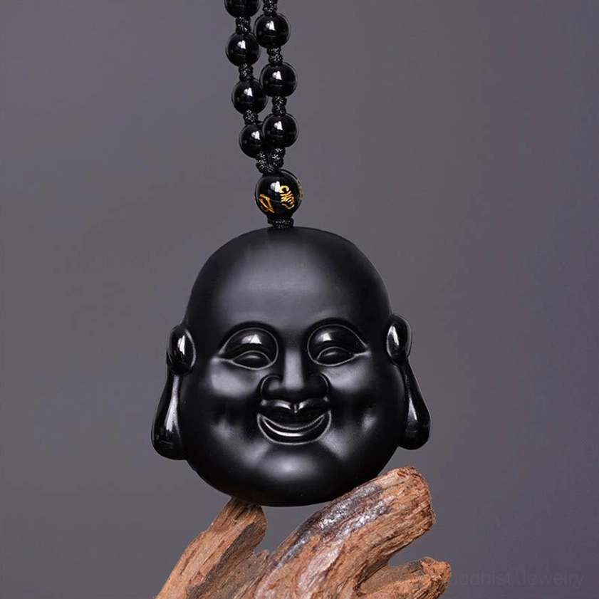 Black obsidian Buddha pendant necklace hanging overhead, showing polished matte finish and beaded chain