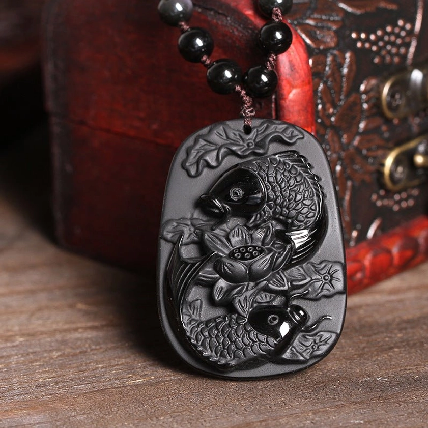 Black Obsidian Buddhist Pendant Necklace with Koi Fish and Lotus carving - frontal view on vintage wooden jewelry box