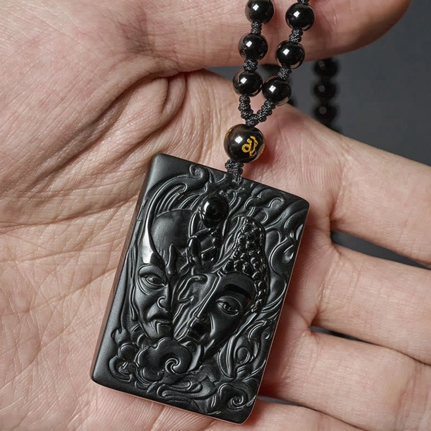 Black obsidian necklace pendant held in hand displaying carved details and authentic stone texture