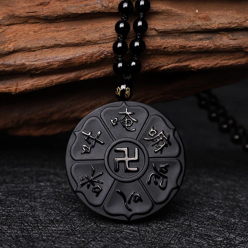 Black obsidian round pendant necklace displayed on dark fabric with beaded chain