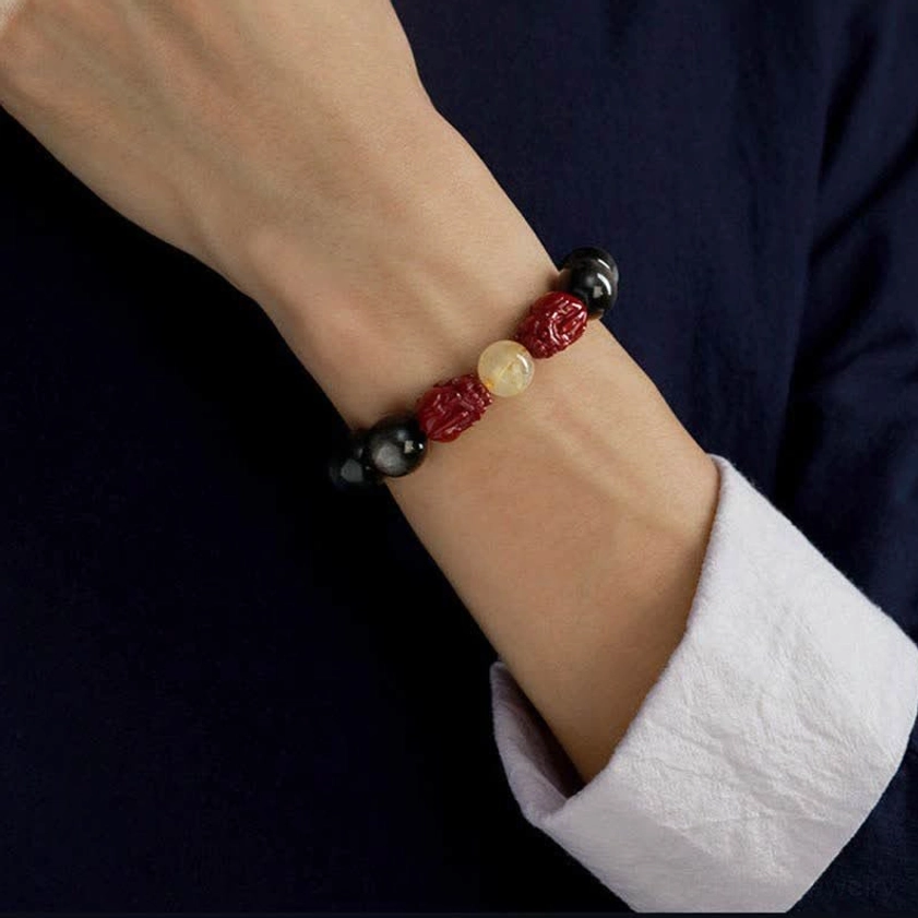 Worn Buddhist bracelet showing gold sheen obsidian, red cinnabar, and spiritual spacer on wrist