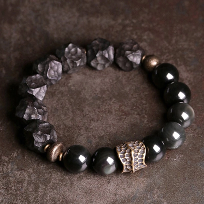 Handcrafted couple bracelet featuring natural black obsidian, ebony wood beads, and vintage bronze metal - close detail flat lay