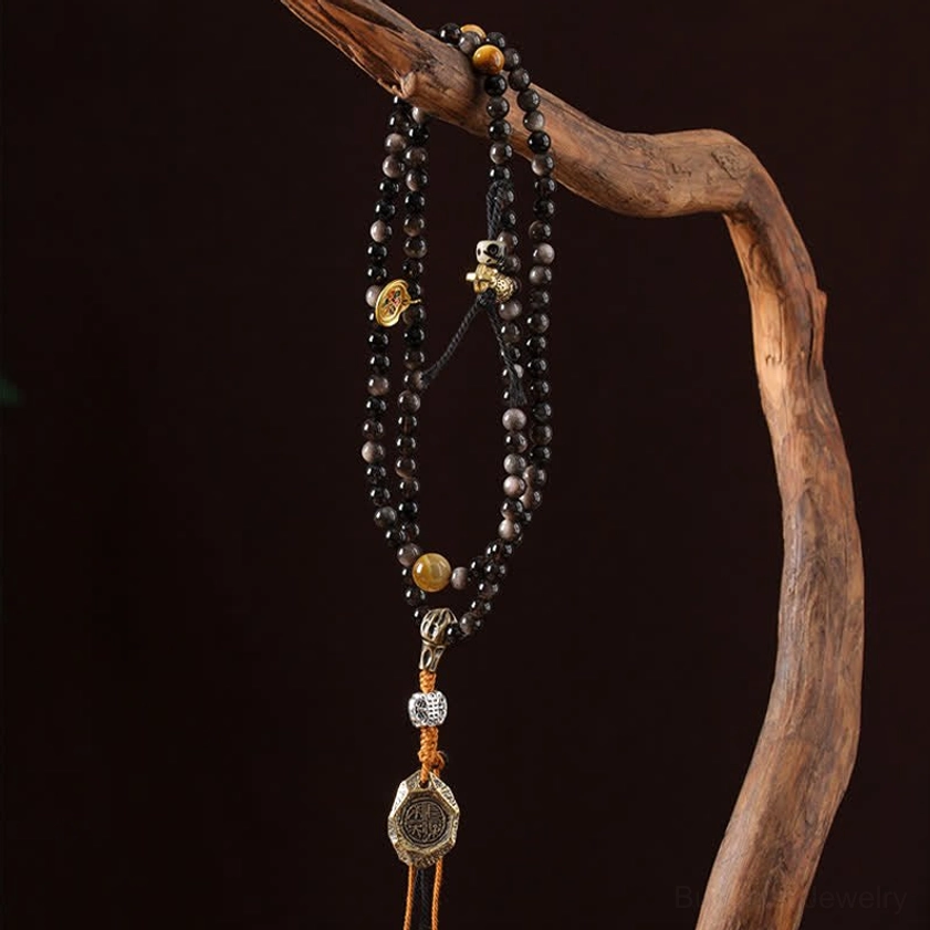 Silver Sheen Obsidian Garuda Buddhist necklace hanging on wooden branch showing pendant and beads