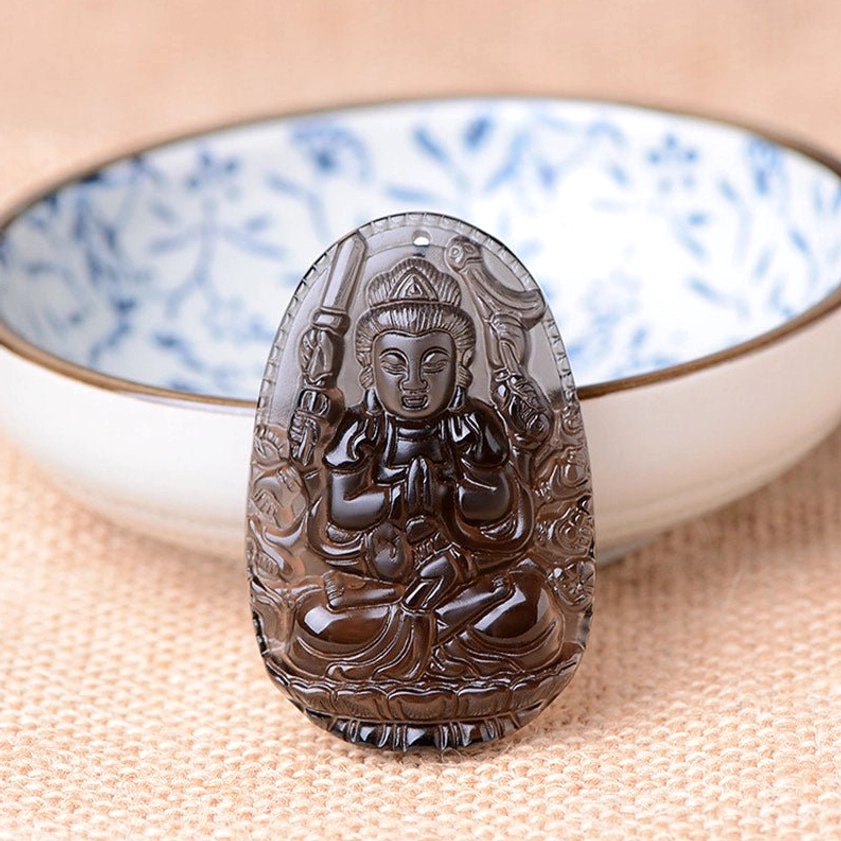 Translucent obsidian thousand-hand Guanyin Buddha pendant showing intricate carving detail and smooth stone texture