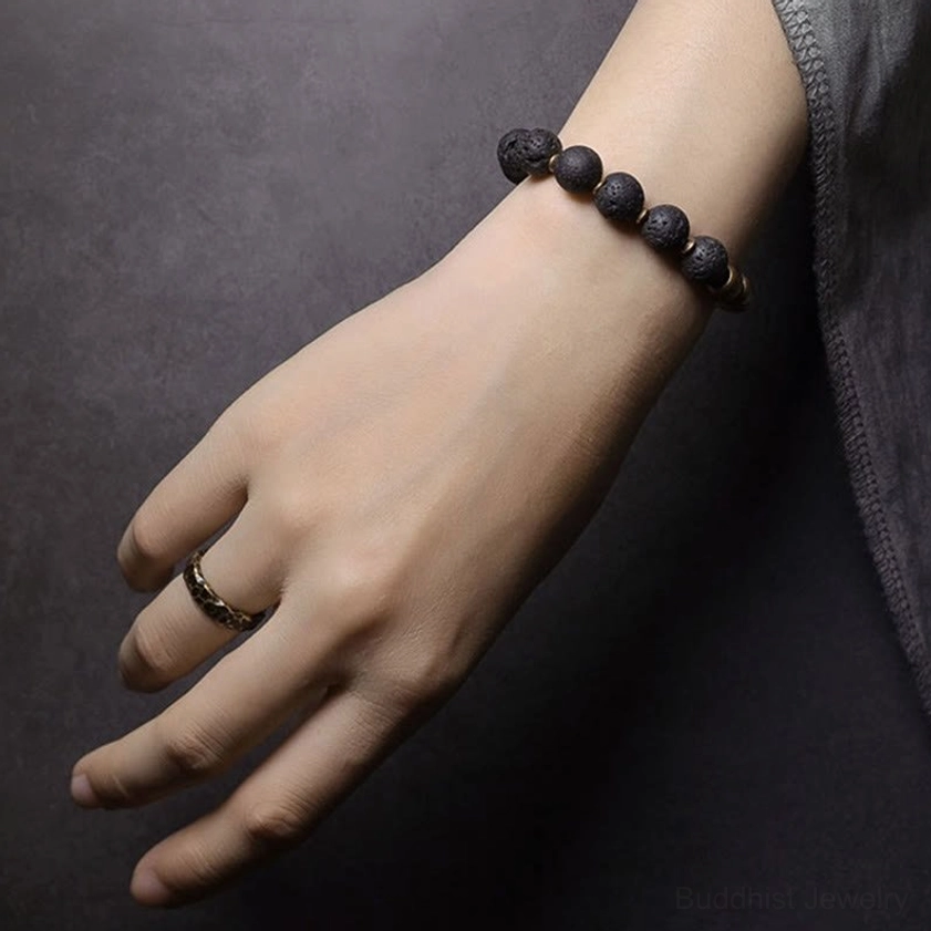 Handmade lava rock obsidian brass bracelet on person's hand, front view showing bracelet styling and bead clarity