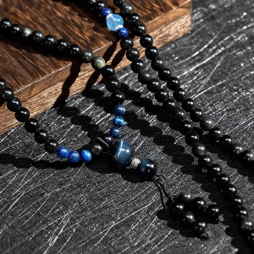 Close-up detailed view of black obsidian prayer beads showing smooth finish, bead joints, and blue central stone