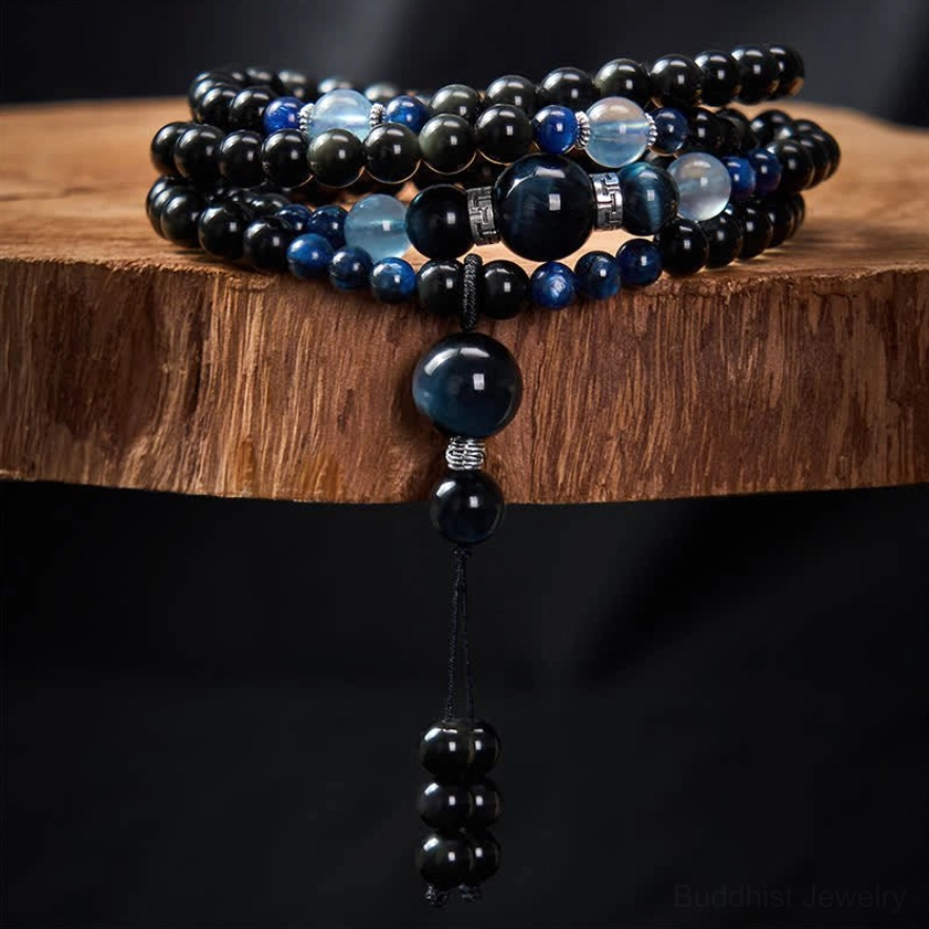 Coiled black obsidian and blue stone mala necklace displayed on wooden stand showing full length and stacked configuration