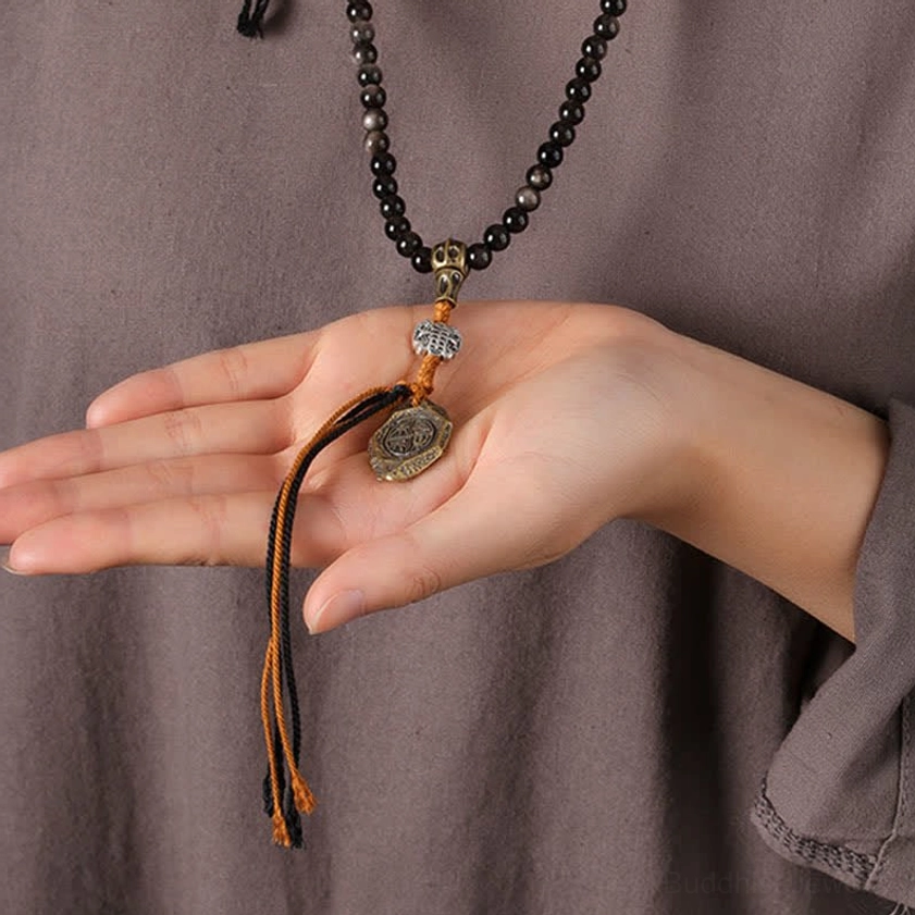 Silver Sheen Obsidian Buddhist mala necklace showing texture of black beads and metal Garuda charm detail