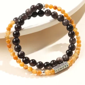 Silver Sheen Obsidian Om Mani Padme Hum double wrap bracelet with gradient yellow-brown and dark obsidian beads, featuring engraved silver mantra charm, displayed on white ceramic plate