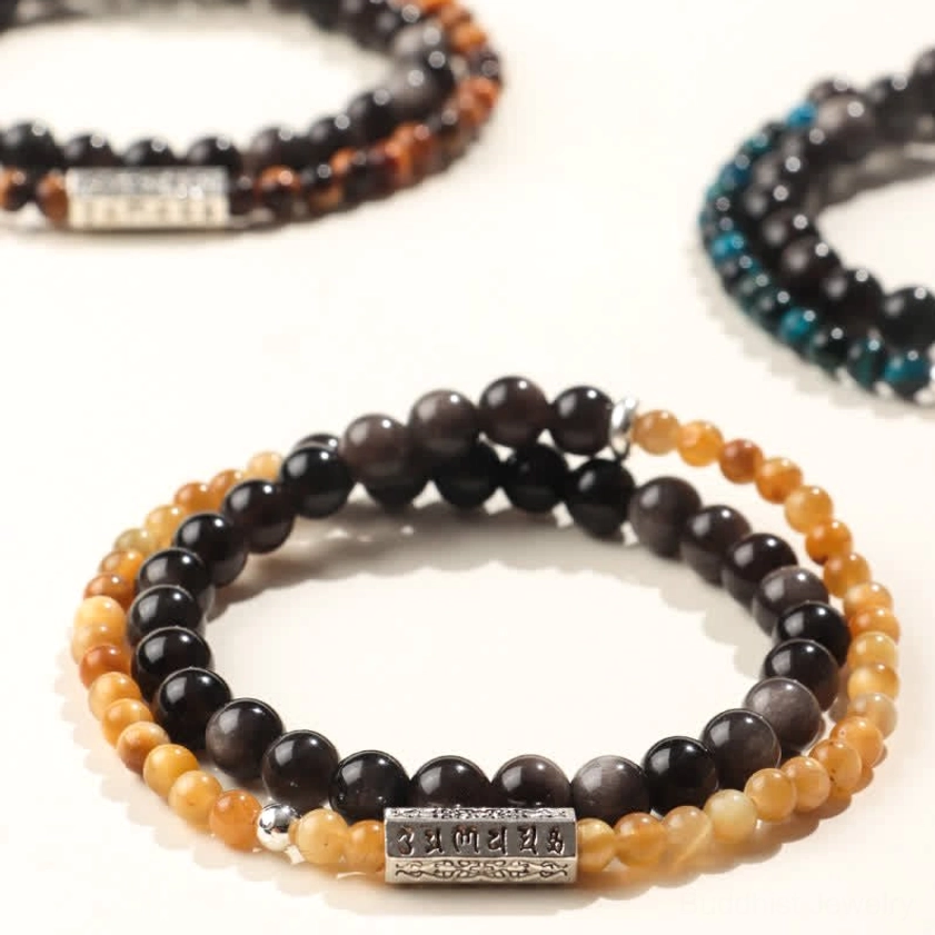 Assorted silver sheen obsidian Om Mani Padme Hum bracelets in multiple color variants, flat lay collection showing different styles and designs