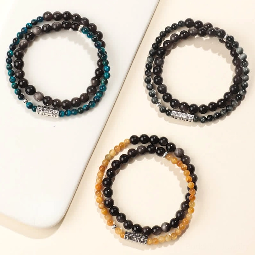 Single and double wrap silver sheen obsidian Buddhist bracelets in three color styles, all featuring engraved Om Mani Padme Hum charms, displayed on white ceramic plate
