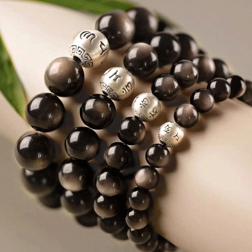 Silver Sheen Obsidian bracelet with hand-engraved Om Mani Padme Hum sterling silver bead showing artisan craftsmanship and natural finish