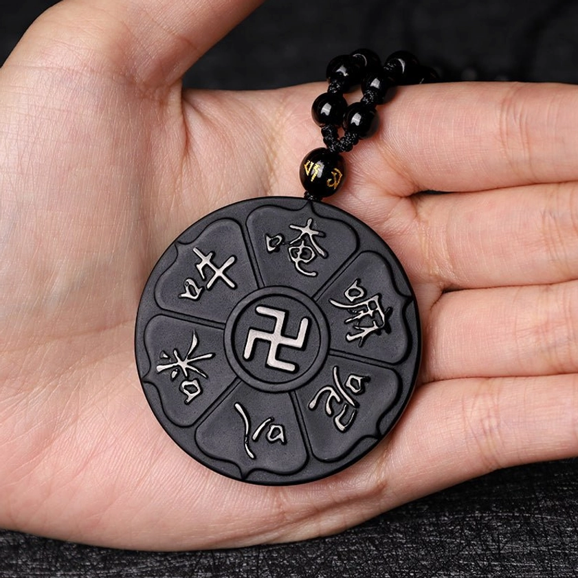 Black obsidian Buddhist pendant necklace held in palm showing full pendant and chain length