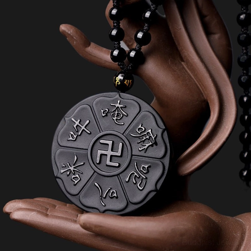 Black obsidian Buddhist pendant necklace held by Buddha hand statue showing complete design