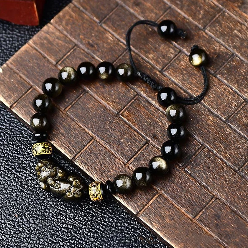 Full layout of gold sheen obsidian Pixiu bracelet, 10mm bead size, showing complete bracelet design with black cord on wooden coaster