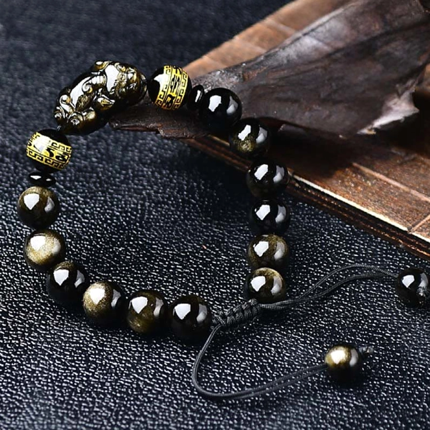 Oblique angle view of gold sheen obsidian Pixiu bracelet with polished round beads and sliding adjustable knot closure