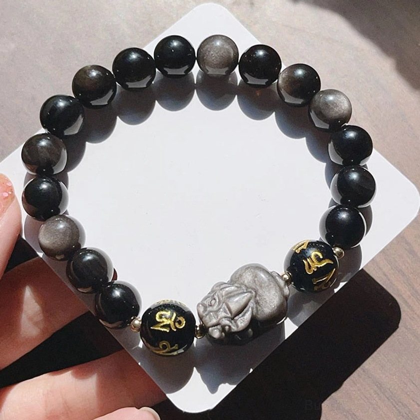 Full view of handcrafted Silver Sheen Obsidian Pixiu protection bracelet laid flat on fabric surface