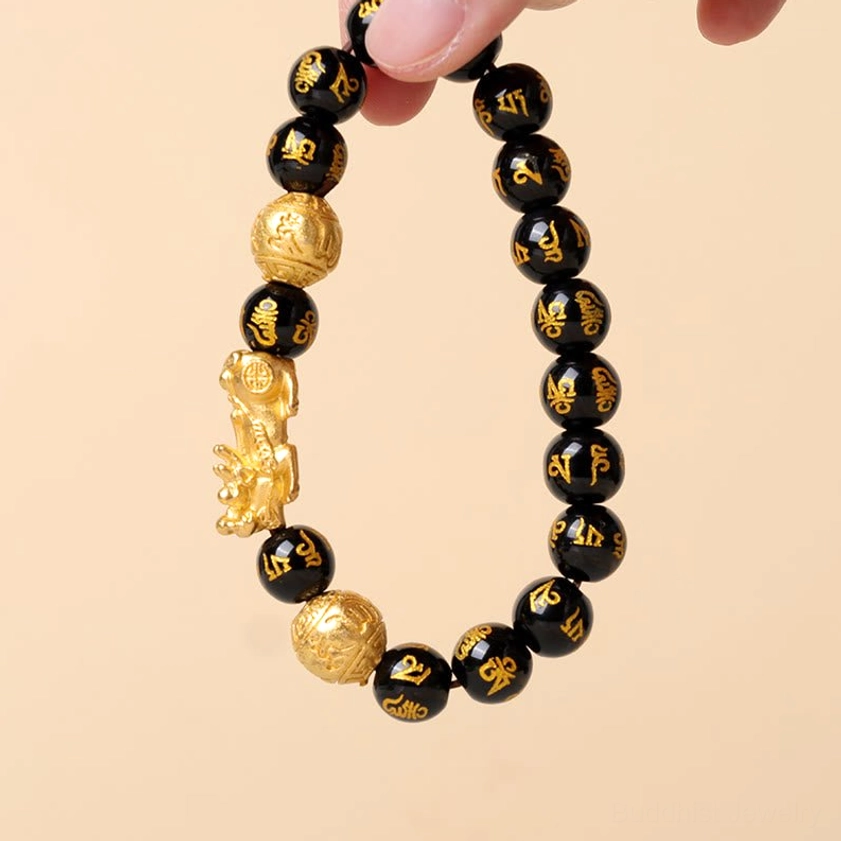 Adjustable black obsidian Pixiu bracelet held in hand showing full circular design with gold Pixiu and smooth stone beads