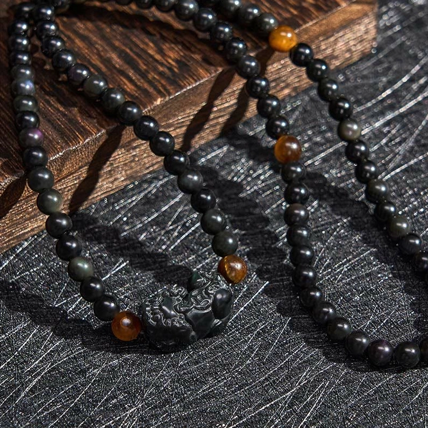 Multi-strand obsidian Pixiu bracelet with hand-carved prosperity charm and tiger eye bead accents overhead view