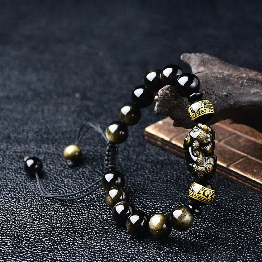 Side angle view of beaded gold sheen obsidian Pixiu bracelet with patterned barrel beads and protective charm