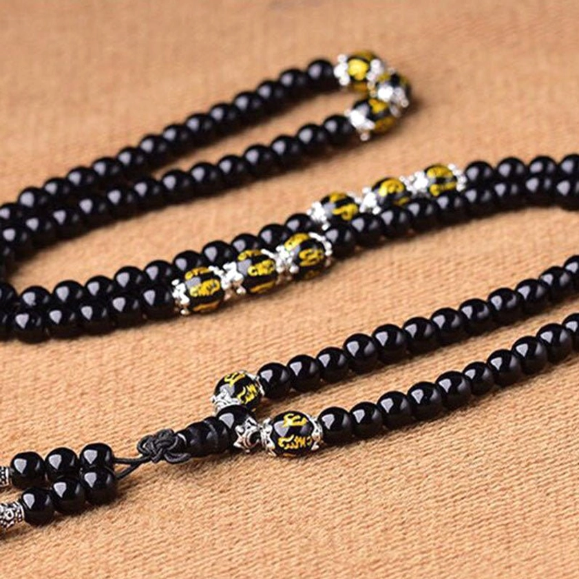 Multiple Black Obsidian Buddhist mala bracelets with 108 beads arranged on burlap showing golden script beads and silver metal fasteners