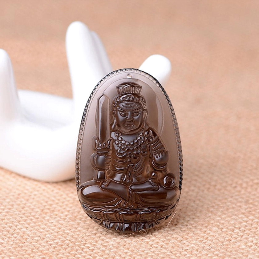 Translucent dark brown obsidian sword-wielding Buddha pendant with smooth polished surface and white background
