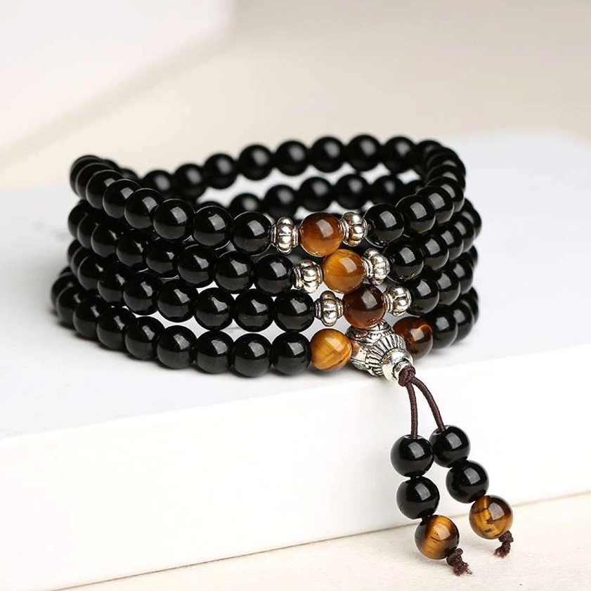 Multi-layer black obsidian tiger eye Buddhist mala flat lay with silver hardware and guru bead tassel
