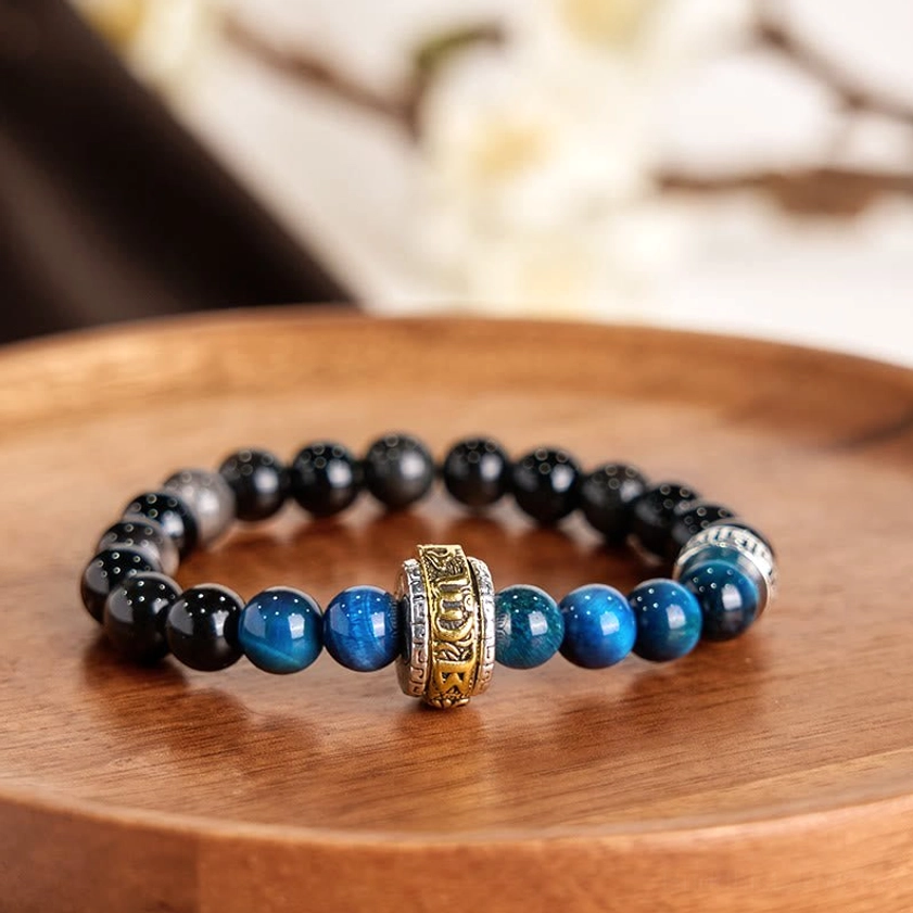 Buddhist protection beaded bracelet featuring mixed Silver Sheen Obsidian and Blue Tiger Eye stones with vintage carved metal mantra spacer bead