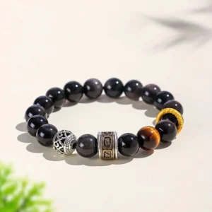 Silver Sheen Obsidian Tiger Eye Om Mani Padme Hum protective beaded bracelet with copper accents on beige background