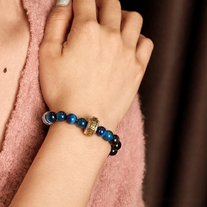Silver Sheen Obsidian and Blue Tiger Eye protection bracelet worn on wrist with pink knitted fabric background, back of hand close-up