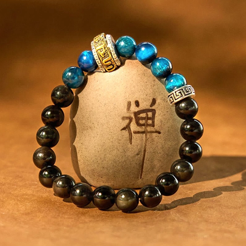 Protection beaded bracelet wrapped around zen ceramic ornament, showcasing Silver Sheen Obsidian, Blue Tiger Eye with Buddhist metal accents