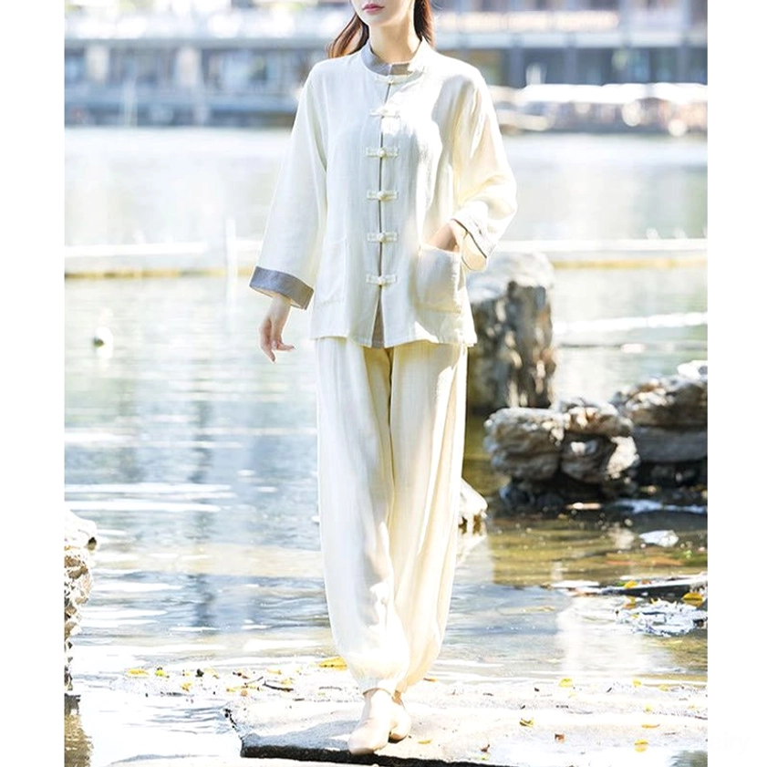Meditation suit in off-white with stand collar frog buttons, front full-body view at lakeside stone platform