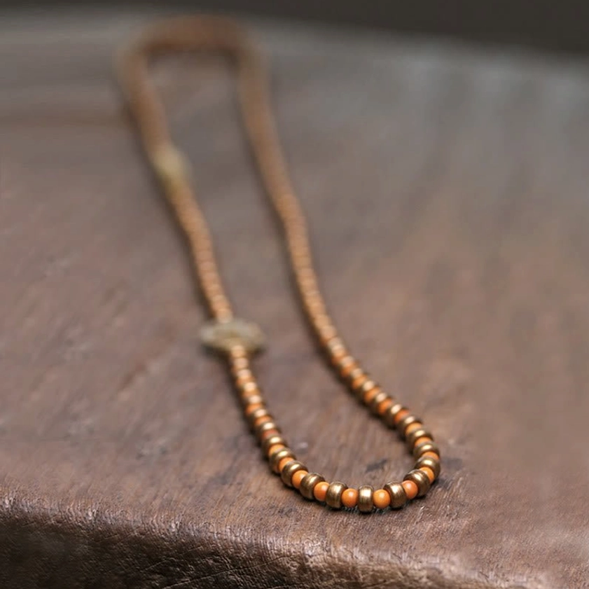 Single-strand olive pit copper bracelet with bronze spacer fastener flat lay view
