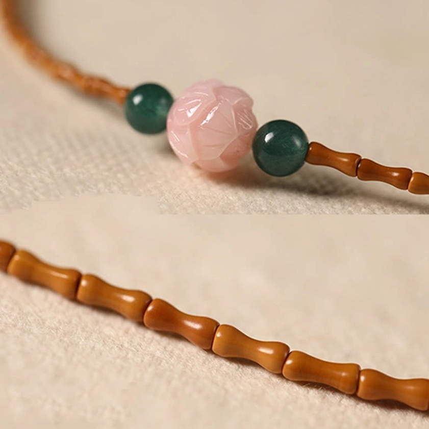 Extreme close-up detail of olive pit lotus bracelet showing hand-carved bamboo beads pink lotus and green round beads