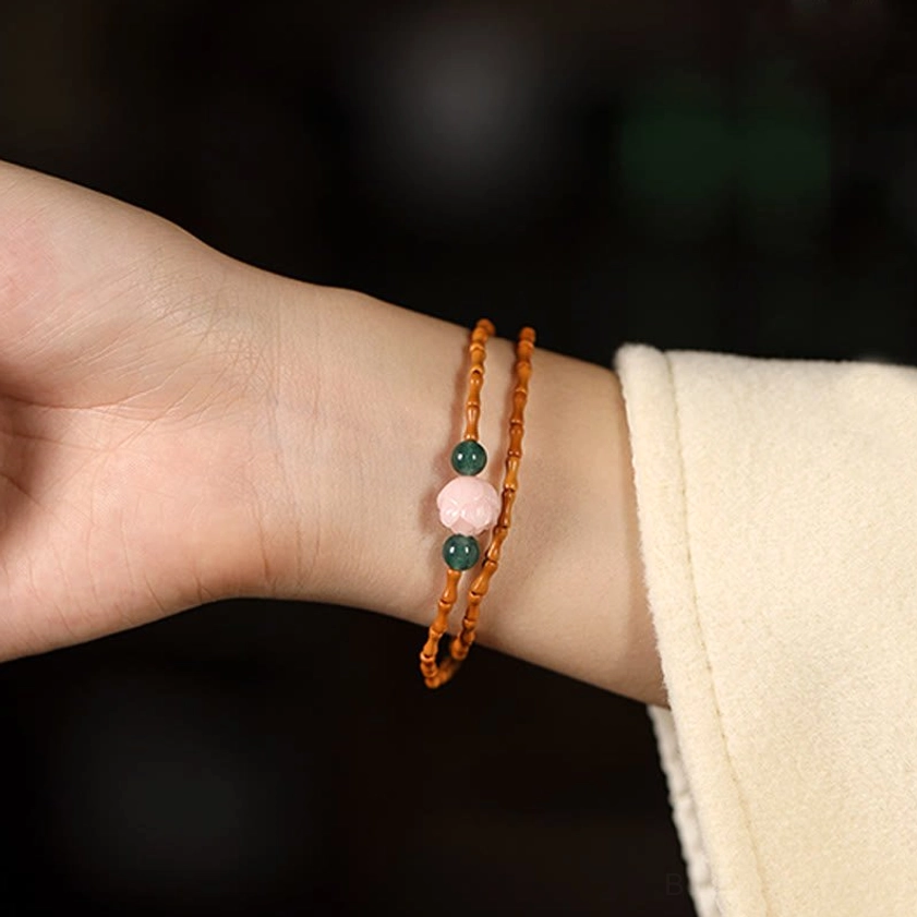 Double strand olive pit lotus beaded bracelet worn on wrist front view with brown beads pink lotus green accents