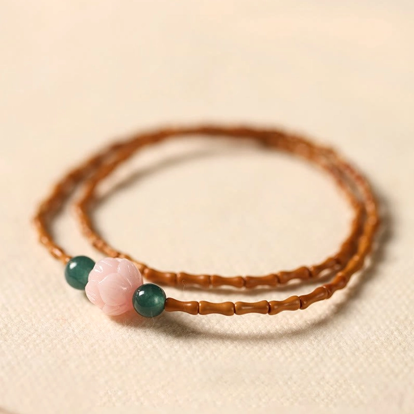 Olive pit lotus double circle bracelet flat lay top view showing bamboo-cut olive pit beads pink lotus bead and green jade accents