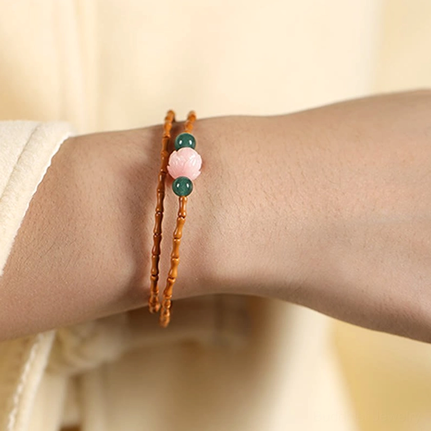 Double layered olive pit lotus bracelet worn on wrist showing side close-up with bamboo beads and green stone accents